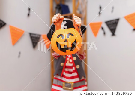 Child in pirate costume holding pumpkin bucket for Halloween trick or treat Child in pirate costume holding pumpkin bucket for Halloween trick or treat 143869750