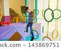 Young boy climbing on rings at indoor playground 143869751