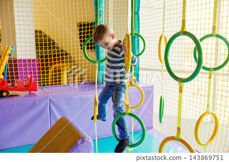 Young boy climbing on rings at indoor playground Young boy climbing on rings at indoor playground 143869751