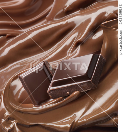 Chocolate pieces on glossy melted cocoa butter swirl Chocolate pieces on glossy melted cocoa butter swirl 143869988