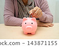 Retired elderly woman putting coins money in piggy bank and worry about monthly expenses and treatment fee payment. 143871155