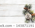 Frosted evergreen branches and pine cones on white wood 143871191