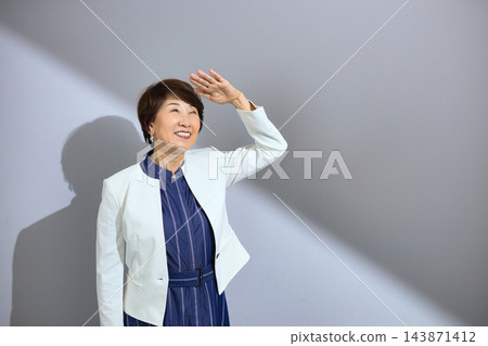 一位六十多歲、穿著外套、笑容燦爛的可愛女士。 143871412