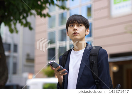一名二十多歲的男子在街上拿著智慧型手機。 143871447