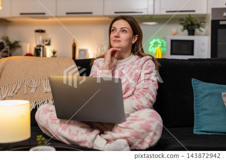 Adult woman with laptop at night deep in thought during remote work online session focused calm deep Adult woman with laptop at night deep in thought during remote work online session focused calm deep 143872942