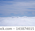 A breathtaking view from the mountaintop: a sea of clouds billowing up and a clear blue sky. 143874015