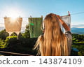 Woman Hanging Laundry Outdoors in Sunlit Mountain Landscape 143874109