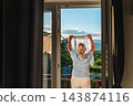 Woman Hanging Laundry by Open Window with Lake View 143874116