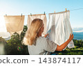 Woman Hanging Fresh Laundry Against Sunny Lake Landscape 143874117