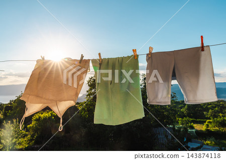 Laundry Drying on Clothesline in Warm Evening Sunlight Laundry Drying on Clothesline in Warm Evening Sunlight 143874118