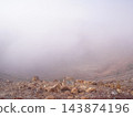 A crater and volcanic rocks shrouded in mist; a desolate mountain landscape with poor visibility. 143874196