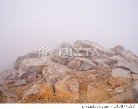濃霧籠罩的岩石山頂;能見度極差的登山景象。 濃霧籠罩的岩石山頂;能見度極差的登山景象。 143874198