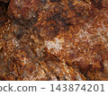 Iron-stained red rock surface; a wild, textured material. 143874201