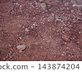 A ground covered in red volcanic gravel, with a texture reminiscent of Mars. 143874204