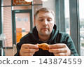 Hungry man eating crispy fried chicken in a fast food restaurant 143874559
