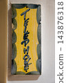 Vertical ceramic plaque reading Telephone hangs on a pale wall in Antibes, France. Soft indoor light reveals glaze, chips, and mottled green ovals framing yellow. 143876318