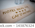 Cream placard reads Hotel Beau Site and Cap d'Antibes with five stars. Two water bottles sit out of focus on a white surface, suggesting a hotel room in Antibes, France. 143876324