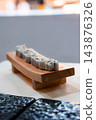 Neatly sliced sushi rolls sit on a small wooden geta board in a refined Maldives resort dining setting with soft ambient lighting and shallow depth of field. 143876326