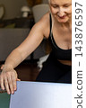 Close up of a smiling middle aged woman hands adjusting a laptop screen before starting an online yoga practice on a mat. Concept of e-learning, digital wellness and home office sports. 143876597