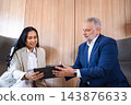 Business colleagues collaborating on digital tablet in office lounge 143876633