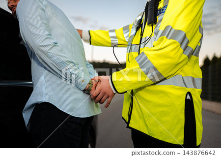 Police officer detaining a man during roadside arrest 143876642