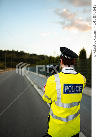 Police officer monitoring highway traffic with a speed camera Police officer monitoring highway traffic with a speed camera 143876645