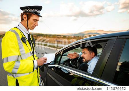 Police officer writing a traffic citation during a roadside stop Police officer writing a traffic citation during a roadside stop 143876652