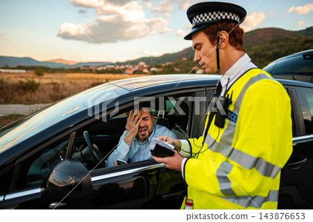 Police officer issuing traffic ticket to frustrated driver during roadside stop Police officer issuing traffic ticket to frustrated driver during roadside stop 143876653