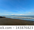 'Black sand beach with blue sky and distant island mountain ' 143876823