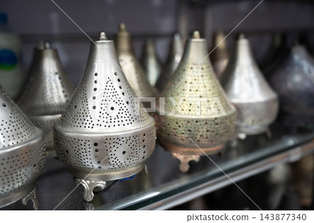 Assortment of perforated metal lanterns displayed on a retail shelf in Egypt. Decorative lighting local trade and tourism shopping 143877340