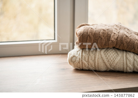 Cozy knitted sweaters on windowsill with copy space Cozy knitted sweaters on windowsill with copy space 143877862