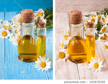 bottle with essential oil and fresh chamomile flowers on a bluewooden background 143878395