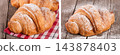 One croissant sprinkled with powdered sugar on a wooden table with napkin 143878403