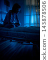 Patient reflects quietly. Hospital bed with contemplative patient. Lone individual sits peacefully in hospital room. Silent patient rests under calming blue illumination overnight 143878506