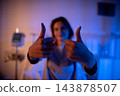 Patient shows confident positive attitude. Smiling individual exhibiting hope and recovery signs. Person with cheerful expression giving thumbs up in healthcare setting 143878507