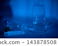 Laboratory mood captured. Scientific setup with neon hue. Test tube and glassware on shiny surface. Reflective laboratory environment with subtle liquid details and glowing tone 143878508