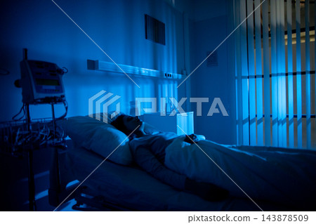 Sleeping patient under monitoring equipment, low blue tones emphasize quiet clinical environment and vigilance of night staff image suggests medical observation and fragile rest 143878509