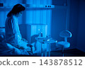 Patient sits on bed near window, pajamas wrinkled, lamp casting soft blue glow, hands folded while staring at distant lights, quiet moment of healing and reflection 143878512