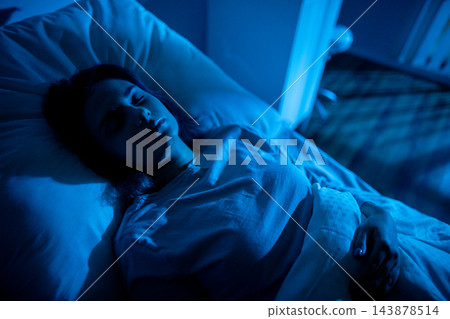 Patient lying awake in hospital bed, closeup portrait reveals weary eyes and tense expression, IV line and gown visible, wakefulness and uncertainty captured in stillness Patient lying awake in hospital bed, closeup portrait reveals weary eyes and tense expression, IV line and gown visible, wakefulness and uncertainty captured in stillness 143878514