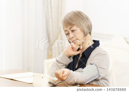 一位老年婦女在客廳量完血壓後情緒低落。 143878989