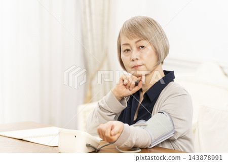 一位老年婦女在客廳量完血壓後情緒低落。 一位老年婦女在客廳量完血壓後情緒低落。 143878991