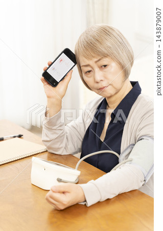 一位老年婦女在客廳量完血壓後情緒低落。 一位老年婦女在客廳量完血壓後情緒低落。 143879007