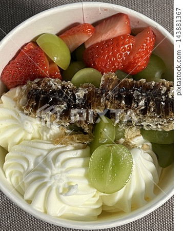Swirled yogurt ice cream dessert served in a cup, smooth creamy texture with glossy surface, topped with fresh fruit pieces, highlighting its refreshing and inviting appearance in detail Swirled yogurt ice cream dessert served in a cup, smooth creamy texture with glossy surface, topped with fresh fruit pieces, highlighting its refreshing and inviting appearance in detail 143881367