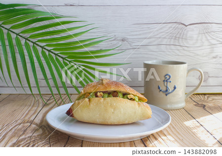 一個白色盤子裡裝著開心果奶油麵包和一杯拿鐵咖啡。 一個白色盤子裡裝著開心果奶油麵包和一杯拿鐵咖啡。 143882098