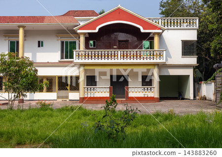 Modern duplex residential house architecture with a green front lawn. Exterior view of a luxury home building in rural countryside setup. 143883260