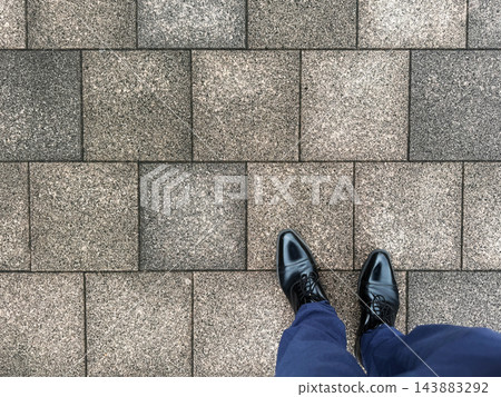 一個穿著皮鞋的男人走在鵝卵石人行道上 143883292