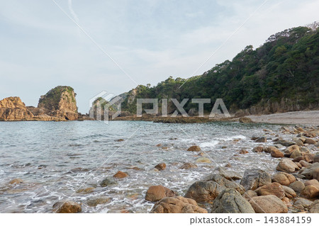 天草西海岸:熊本縣天草市,一個被岩石環繞的海灣和鵝卵石海灘。 天草西海岸:熊本縣天草市,一個被岩石環繞的海灣和鵝卵石海灘。 143884159