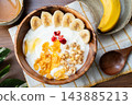An overhead view of yogurt and bananas. 143885213
