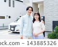 A young couple standing close together in front of their house 143885326