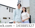 A young couple standing close together in front of their house 143885327